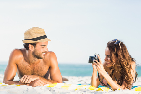 Girlfriend taking picture of boyfriend on a sunny dayの写真素材
