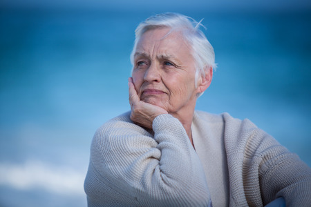 Thoughtful mature woman looking away on the beachの写真素材