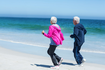 Cute mature couple running together on the beachの写真素材