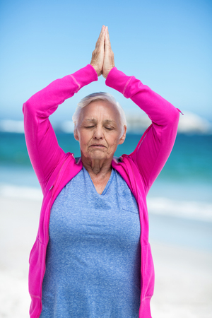 Thoughtful mature woman meditating on the beachの写真素材
