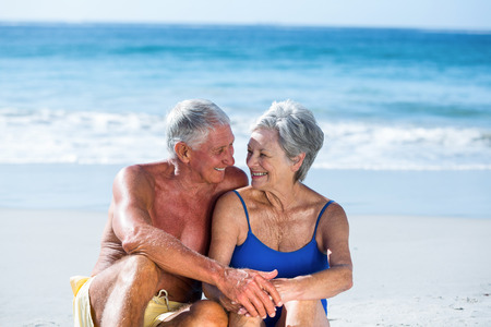 Cute mature couple sitting on the beach on a sunny dayの写真素材