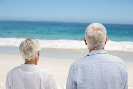 Rear view of a senior couple holding hands at the beachの写真素材