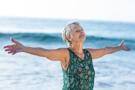 Senior woman outstretching arms at the beachの写真素材