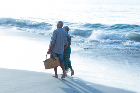 Senior couple with a picnic basket at the beachの写真素材