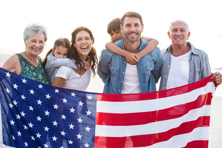 Happy family with an american flag at the beachの写真素材