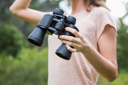 Woman holding binoculars in the countrysideの写真素材