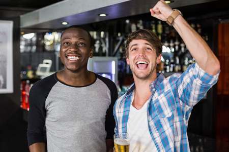 Happy friends watching sport in a barの写真素材