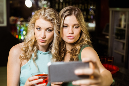 Smiling friends taking a selfie in a barの写真素材