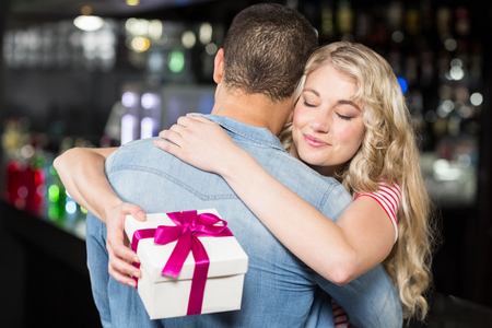 Cute couple hugging having a gift in a pubの写真素材