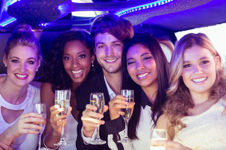 Happy friends drinking champagne in limousineの写真素材