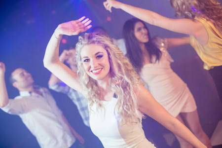 Happy friends dancing cheerfully in night clubの写真素材