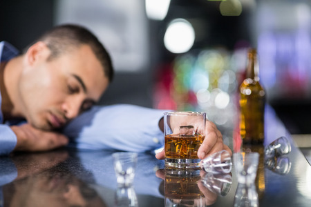 Tired man having a whiskey and sleeping on a counter in a pubの写真素材