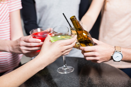 Group of friends toasting with beer and cocktails in a nightclubの写真素材