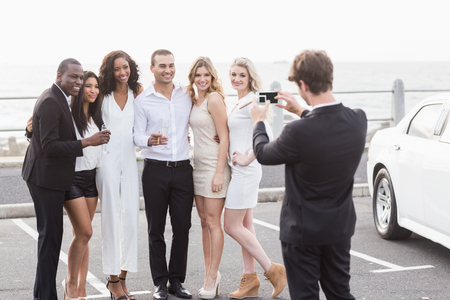 Well dressed people taking pictures next to a limousine on a night outの写真素材