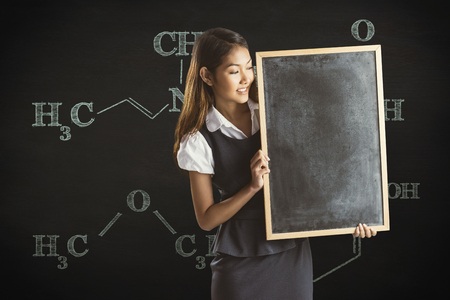Smiling businesswoman holding a blackboard against black backgroundの写真素材