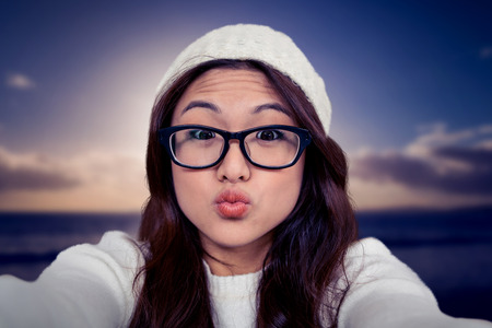 Asian woman making faces against scenic view of sea against skyの写真素材