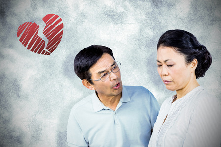 Older asian couple having an argument against red heartの写真素材