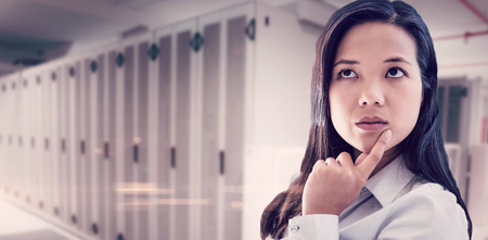 Thoughtful businesswoman with finger on chin against data center