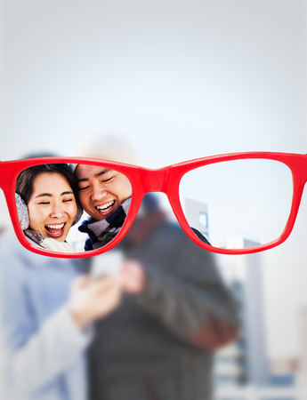 Cheerful couple looking at the smart phone against glassesの写真素材