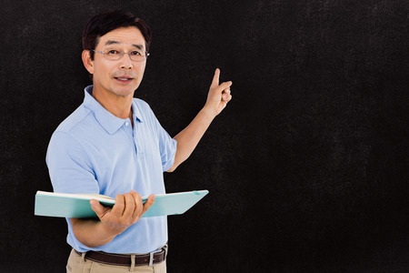 Elderly man pointing behind him against blackboardの写真素材