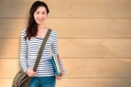 Cheerful woman with shoulder bag and files against bleached wooden planks backgroundの写真素材