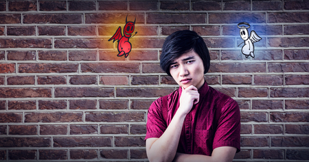 Serious hipster holding his chin against red brick wall