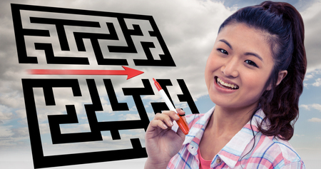 Smiling woman against wooden wall with notes on it against maze with arrow in skyの写真素材