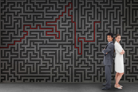 Portrait of business people standing back-to-back against grey mazeの写真素材