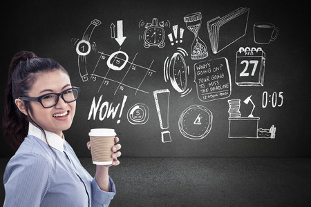 Businesswoman holding disposable cup and looking at wall with notes against black wallの写真素材