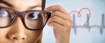 Close up view of a businesswoman holding her eyeglasses against medical background with red ecg lineの写真素材
