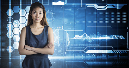 Businesswoman with crossed arms against hologram interface in office overlooking cityの写真素材