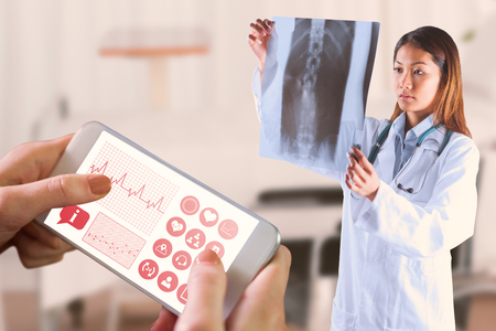 Asian doctor checking MRI scan against bright white room with windowsの写真素材