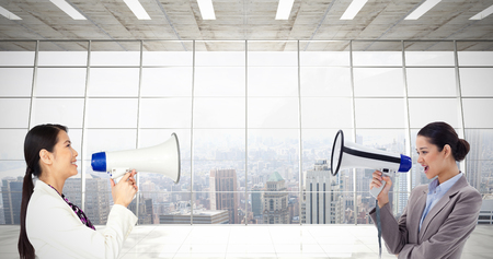 Portrait of a businesswoman shouting through a megaphone against modern room overlooking cityの写真素材