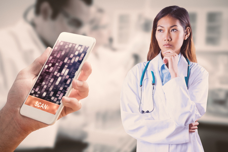 Focused asian woman thinking against yellow, red, orange dna strandsの写真素材
