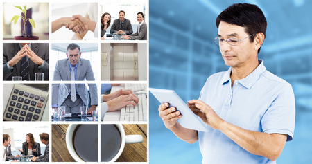 Man using digital tablet while standing against modern room overlooking cityの写真素材