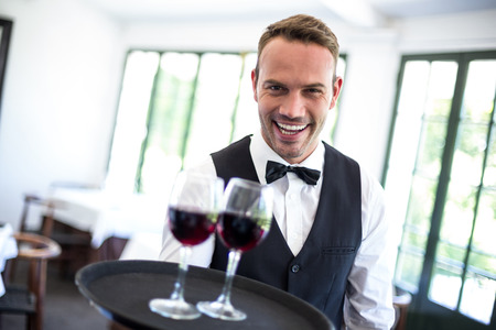 Waiter holding tray with red wine in a commercial kitchenの写真素材