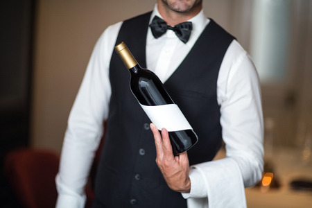 Waiter presenting red wine in a commercial kitchenの写真素材