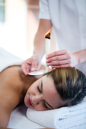 Woman receiving ear candle treatment at spaの写真素材