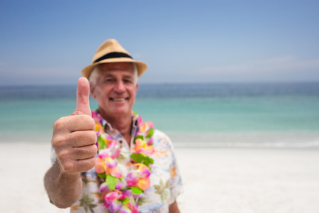 Happy senior man showing is thumbs up on the beachの写真素材
