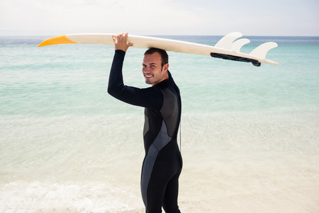 Portrait of surfer holding surfboard over head on the beachの写真素材
