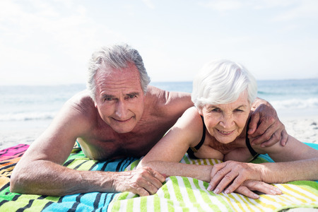 Portrait of happy senior couple lying on the beach on a sunny dayの写真素材