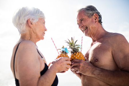 Senior couple having pineapple cocktail on beach on a sunny dayの写真素材