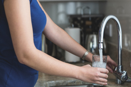 Close-up of woman washing a glass in kitchen sink at homeの写真素材