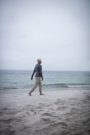 Senior man walking on the beach on a sunny dayの写真素材