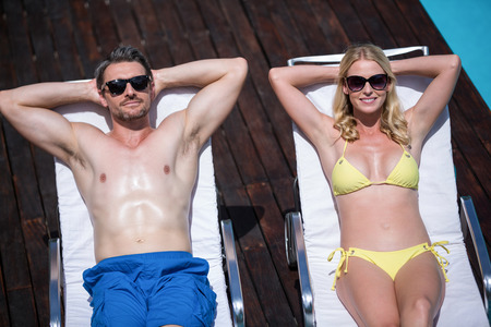 Couple relaxing on a sun lounger near the poolの写真素材