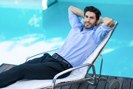 Portrait of smart man relaxing on sunlounger near poolの写真素材