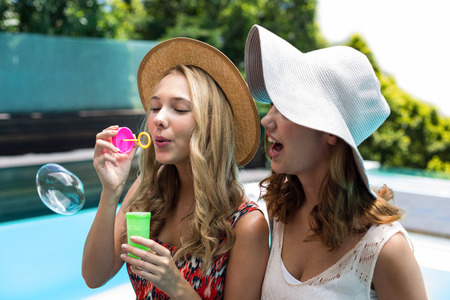 Beautiful blowing bubble wand near poolの写真素材