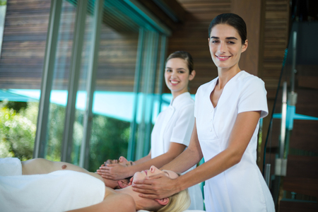 Couple receiving a face massage from masseur in spaの写真素材