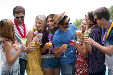 Group of friends wearing a garland and holding a glass of cocktail on a sunny dayの写真素材