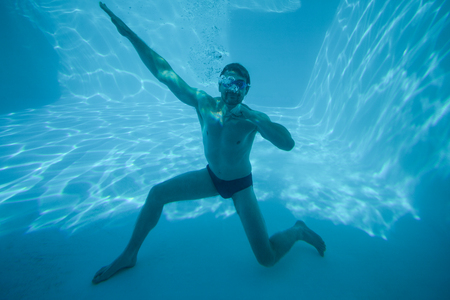 Man posing underwater in swimming pool at resortの写真素材